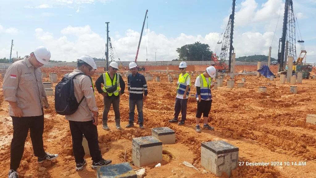 Teknisi menggunakan APD lengkap saat melakukan uji pondasi di lapangan
